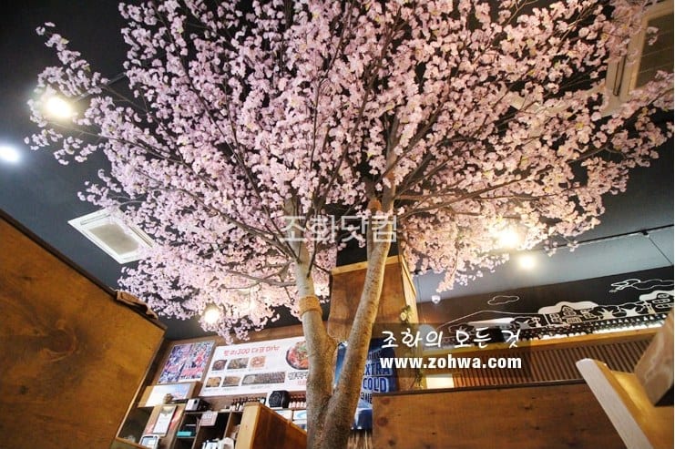 인천 닭권브이치킨토리 300점 — 부스 사이 솟은 벚꽃나무
