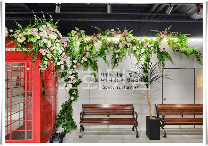 세종시 글린정원 세종점 — 빨간 전화부스와 벤치 위로 꽃 넝쿨을 드리운 거리 연출