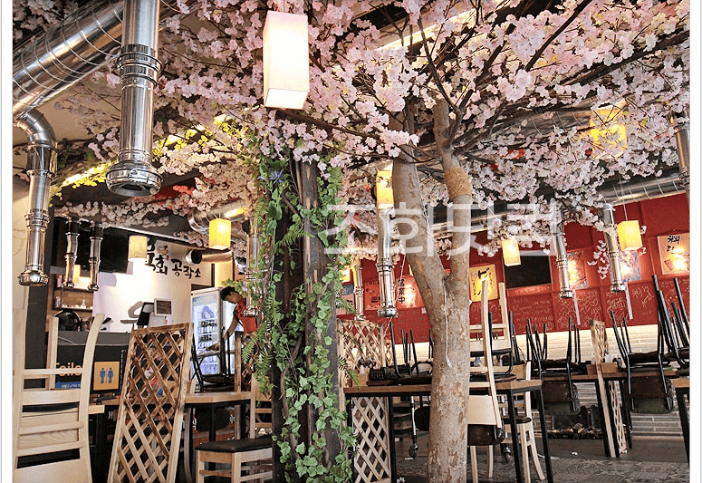 전주 육회공작소 전북대점 — 넝쿨 기둥과 벚꽃이 어우러진 모임 좌석