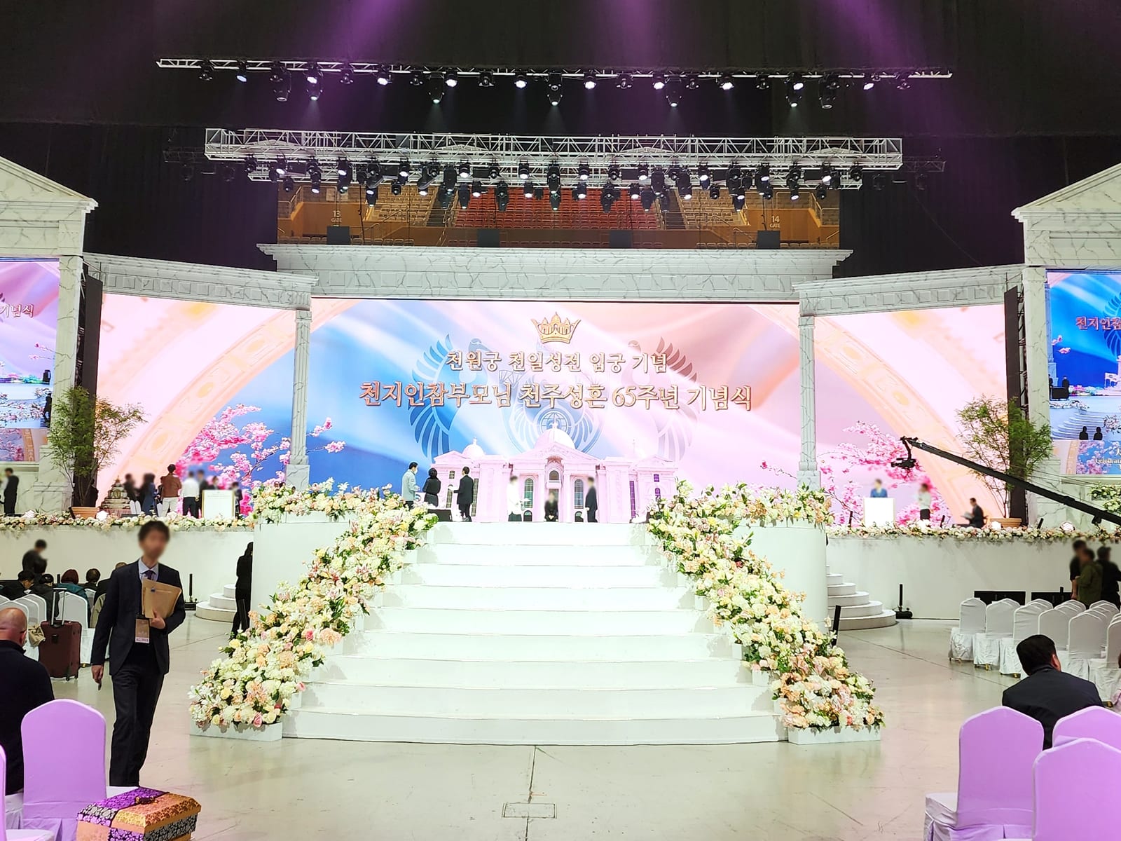 경기 가평 종교단체 행사장 — 흰 계단 양옆을 파스텔 조화 꽃으로 가득 채운 대형 기념식 무대
