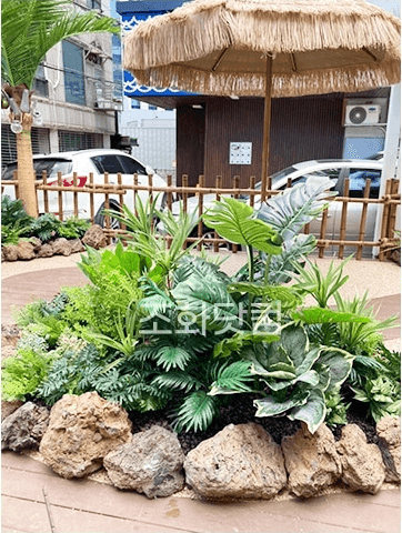서울 에이스크랩 강남점 — 초가 파라솔과 야자수로 꾸민 입구 포토존
